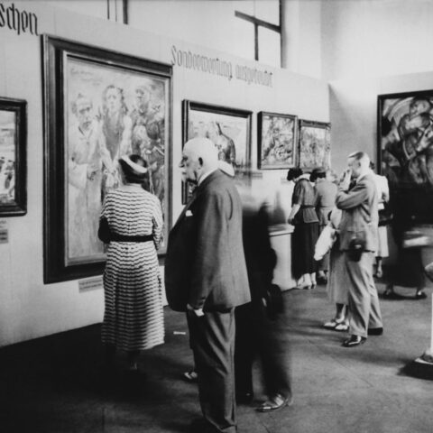 Ziyaretçiler, Dejenere Sanat sergisinde. Resimde Lovis Corinth'in Ecce homo'su (soldan ikinci) ve Franz Marc'ın Mavi Atlar Kulesi (sağdaki duvar) ile Wilhelm Lehmbruck'un Diz Çökmüş Kadın heykeli görülüyor. Fotoğraf: MoMA